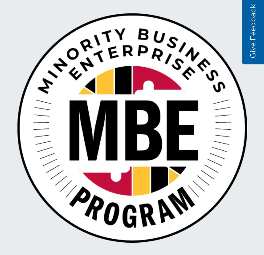 1290a959-27eb-482d-a634-fb6159cac9d4 Round logo for the Minority Business Enterprise (MBE) Program, featuring large "MBE" text and a design inspired by the Maryland state flag.